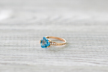 Gold ring with blue topaz on a light background