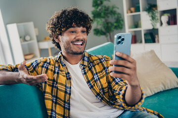 Photo of cheerful handsome guy sit sofa communicate vlogging record video make selfie smart phone...