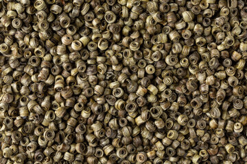 Close-up of  hand rolled white tea, jade ring, as background. Dry tea leaves for chinese tea ceremony. Top view.