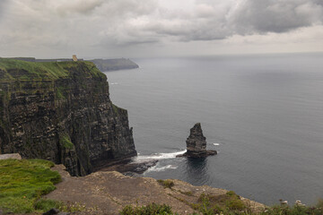 Horizontal view of cliff landscape with cloudy sky and green meadow in Ireland