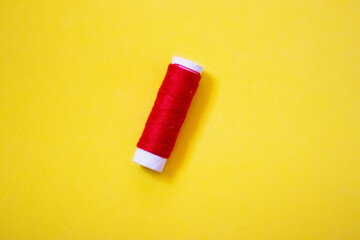 Sewing thread spool, isolated on yellow wbackground. Colored threads are used by factories in the clothing industry. The thread is wound on a spool. Colored scrolls