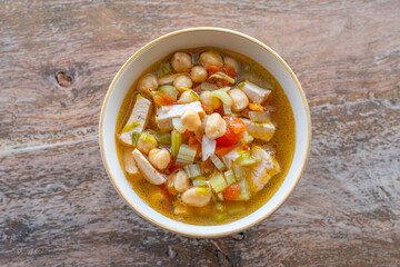 Chicken Chickpea and Celery Soup in ceramic plate over wooden background. Top view.