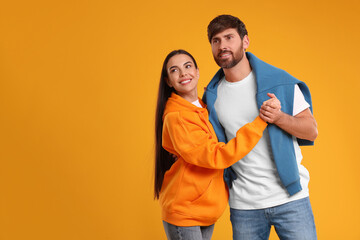 Happy couple dancing together on orange background, space for text