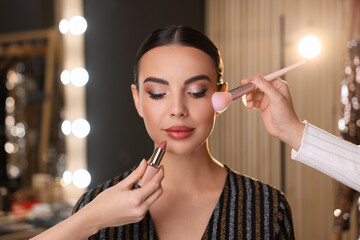 Makeup artists working with beautiful woman in dressing room