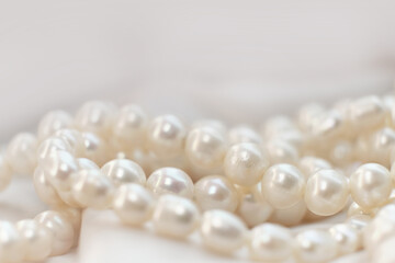 A string of pearls nestles softly on a light fabric, their subtle glow embodying elegance. It's a...