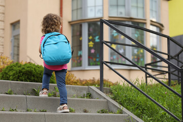 Little girl walking to kindergarten outdoors, back view. Space for text