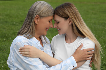 Obraz premium Happy mature mother and her daughter hugging outdoors