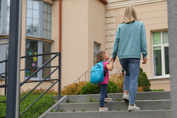 Woman and her little daughter on their way to kindergarten outdoors, back view. Space for text