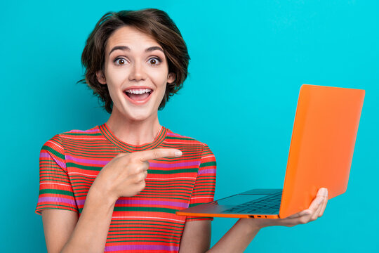 Portrait of overjoyed girl with short hair wear stylish t-shirt directing at laptop recommend eshop isolated on teal color background