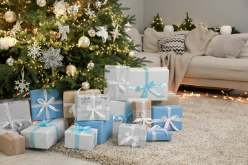 Many gift boxes under decorated Christmas tree in room