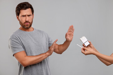 Stop smoking concept. Man refusing cigarettes on grey background