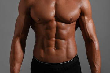 Fototapeta na wymiar Young bodybuilder with muscular body on grey background, closeup