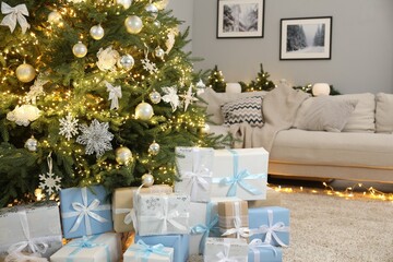 Many gift boxes under decorated Christmas tree in room