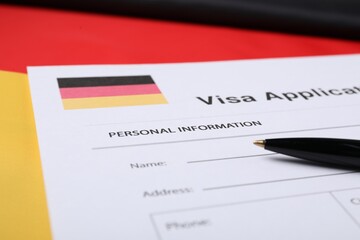Immigration to Germany. Visa application form and pen on flag, closeup