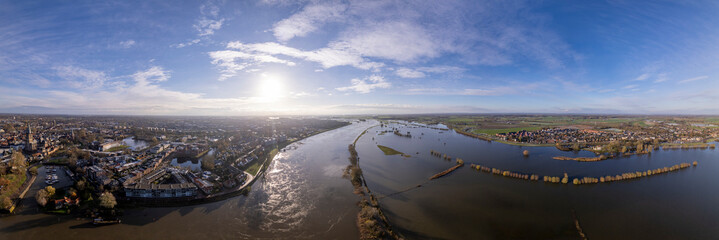 Floodlands overflown during extreme high water level of river IJssel in Zutphen, The Netherlands, against a blue sky in the morning. Aerial weather and climate concept.