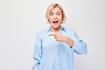 Young blond woman in casual pointing aside finger, demonstrating empty space for product or text...