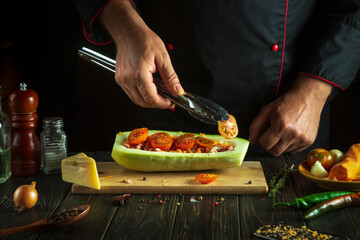 Professional chef prepares a stuffed zucchini boat on the kitchen table of the hotel. Delicious dinner with national dish stuffed squash