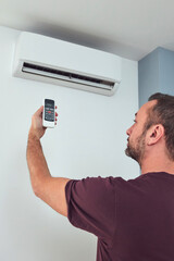 Man holding a modern AC unit remote.