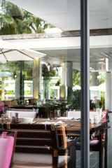 Hotel restaurant space with tables set for dinner at luxury resort, view through by window.