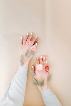 hands flowers on background. Close-up of beautiful intricate female hands with pink flowers on a white background. Hand care concept, anti-wrinkle, anti-aging cream. High quality photo
