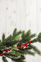 Fototapeta na wymiar Christmas fir branch with decor and pine cone on a light wooden background, copy space. Place for text. Artificial spruce branch. Selective focus
