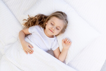 cute baby girl sleeping on a bed on a white cotton pillow under a blanket, healthy baby sleep at...
