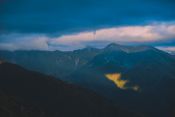 The ray of light hitting the side of a rocky mountain. Cloudy weather after a summer storm in the Carpathian Mountains of Romania