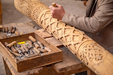 man crafting a wooden beam with his hand in Old traditional way, old traditional handcraft, Khiva,...