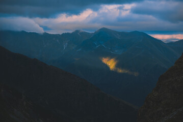 The ray of light hitting the side of a rocky mountain. Cloudy weather after a summer storm in the Carpathian Mountains of Romania