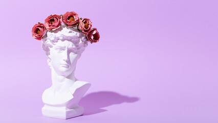 Card with an artificial statue of David in a wreath of flowers on a purple background. Creative...