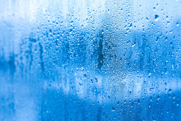 Blue background of glass of metal-plastic window with water droplets condensation indoors room....