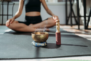 Incense burning in rin gong with woman exercising on mat in background