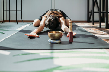 Woman practicing Balasana pose on yoga mat at home