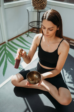 Woman practicing music therapy with rin gong in hand at home