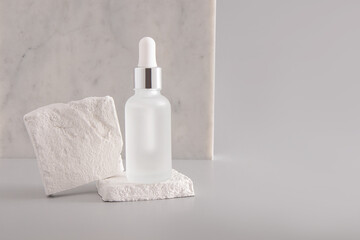 Cosmetic, Facial Skin Care Serum in White Matte Bottle with Dropper on Grey Background with White Brick Plates. Front view. Product presentation.