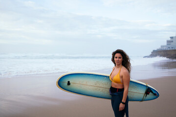 Confident young woman with surfboard at beach on vacation