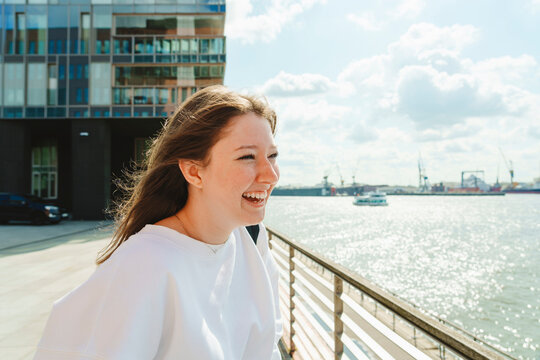 Cheerful teenage girl enjoying weekend by Elbe river at harbor