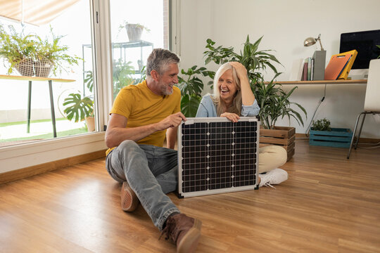 Happy couple sitting with solar panel at home