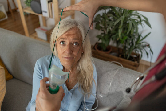 Doctor putting oxygen mask on patient's face at home