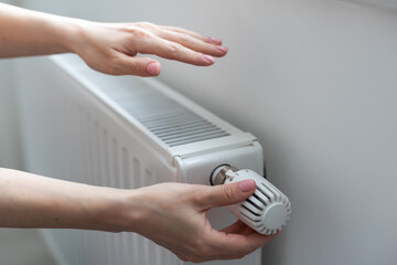 Woman adjusting temperature on heating radiator, Energy crisis concept in Europe, Rising costs in private households for gas bill due to inflation and war