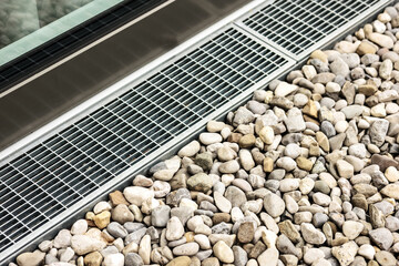 Drainage Stone Gravel Floor around House Outside with Grid Grate by Window. French Drain System.
