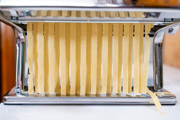 Cut Pasta in Domestic Kitchen,Fresh pasta and pasta machine on the kitchen counter while rolling...