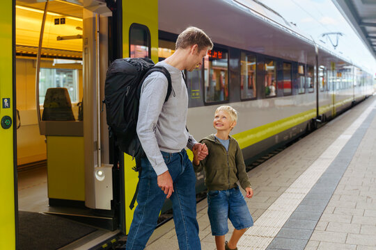 Happy son and father walking on platform in front of train
