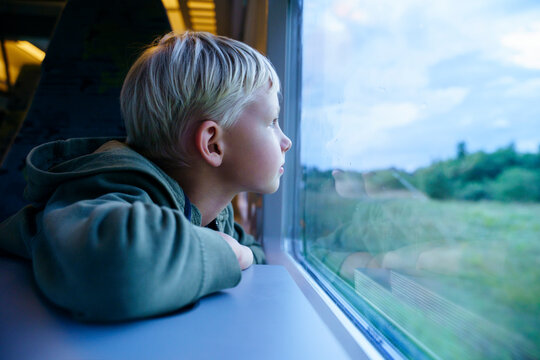 Contemplative blond boy looking through train window