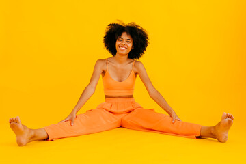 Smiling woman spreading legs against yellow background