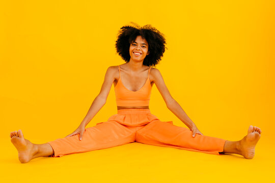 Smiling woman spreading legs against yellow background