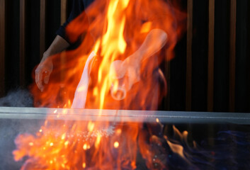 Chef cooking at stove with fire flame, close-up, selective focus