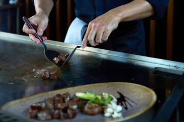 Professional chef cooking delicious juicy beef steak on restaurant stove, selective focus