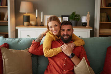 Smiling couple hugging on sofa in living room