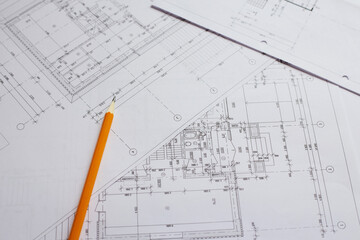 pencil and office tools for writing on the blueprint of construction industry. Place the rolls on a desk over blurred blueprint for construction industry background.